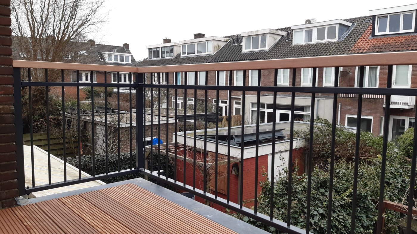 Het hekwerk langs de rand van het dakterras met uitzicht over de daken