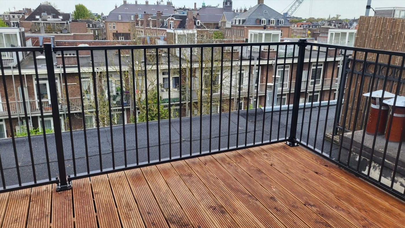 Zwart balkonhekwerk A03 rond een dakterras met hardhouten vlonder in Amsterdam