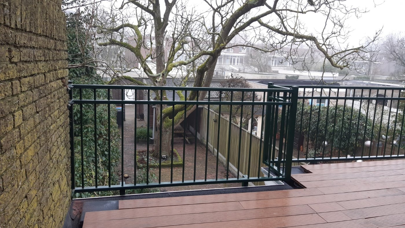 Donkergroen stalen balkonhekwerk langs een dakterras in Tilburg