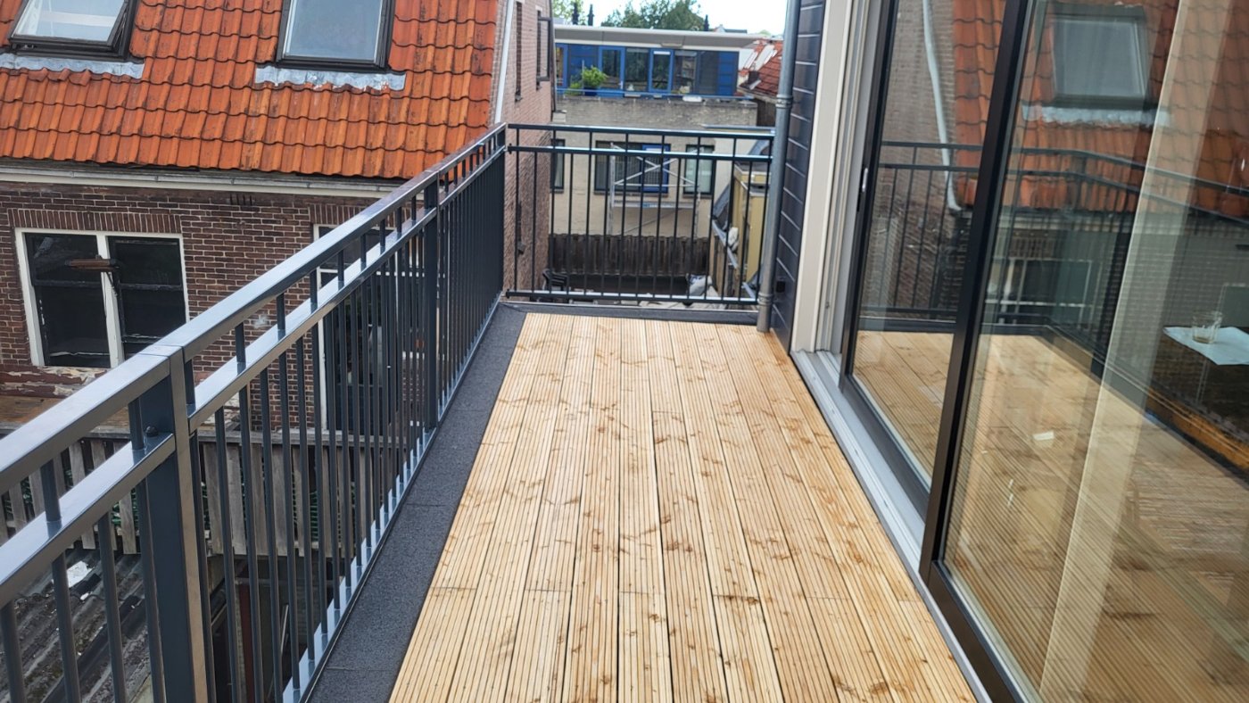 Het dakterras met verse houten vlonder en de balustrade langs de rand