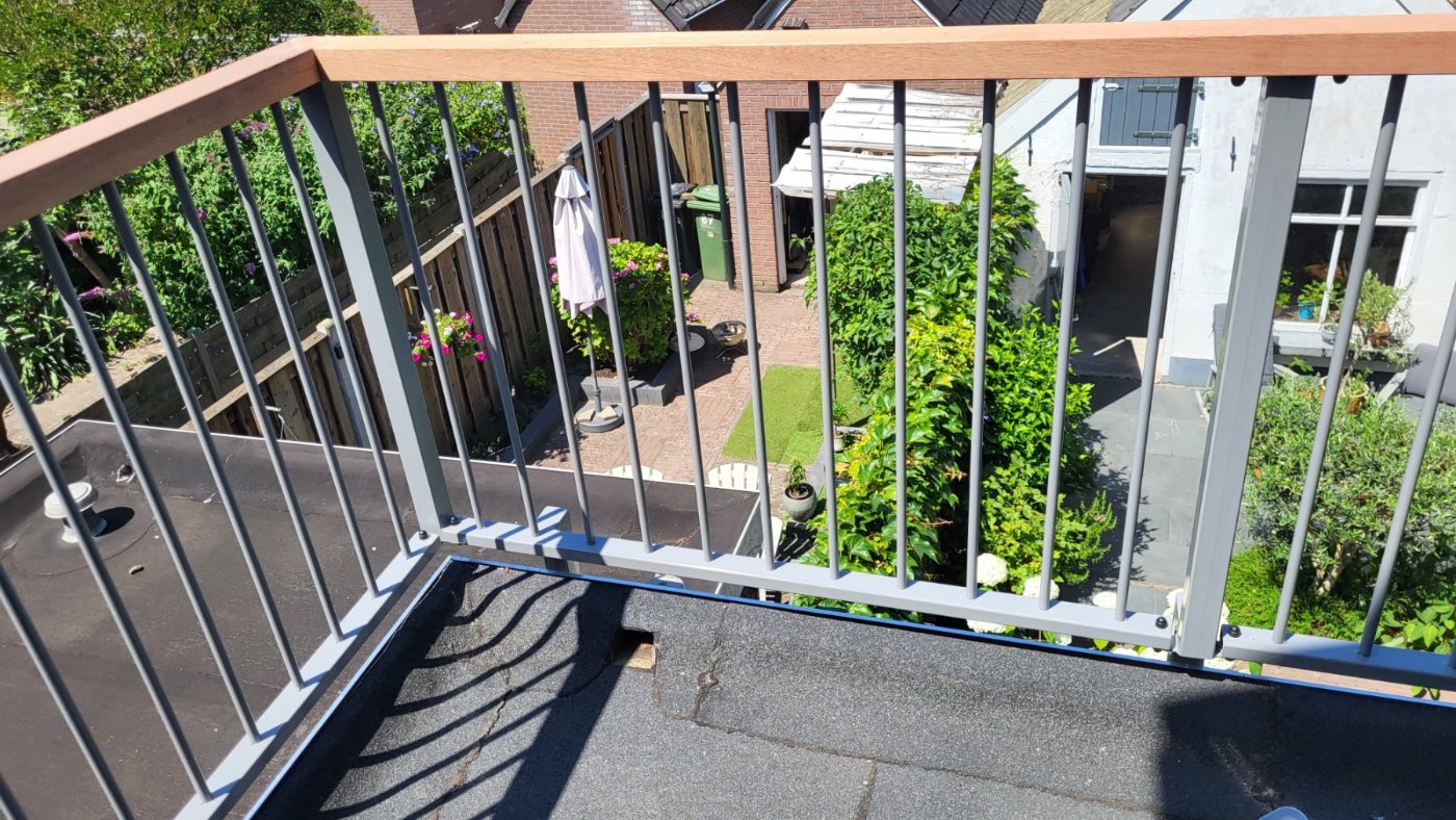 Houten handregel op de balustrade met uitzicht over de tuinen
