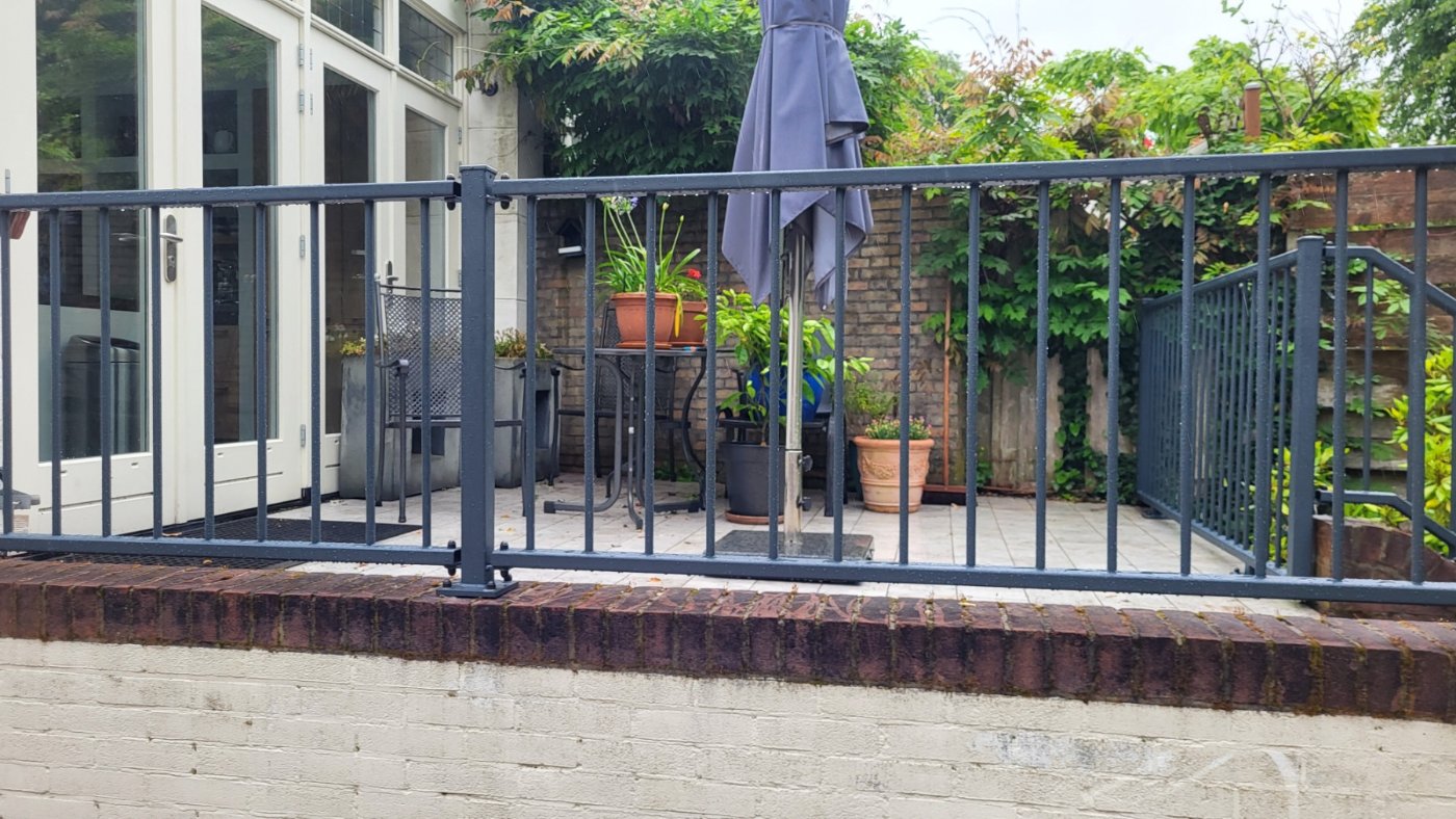 Stalen balustrade model A03 in RAL 7016 op de keermuur van een verhoogd terras in Bussum