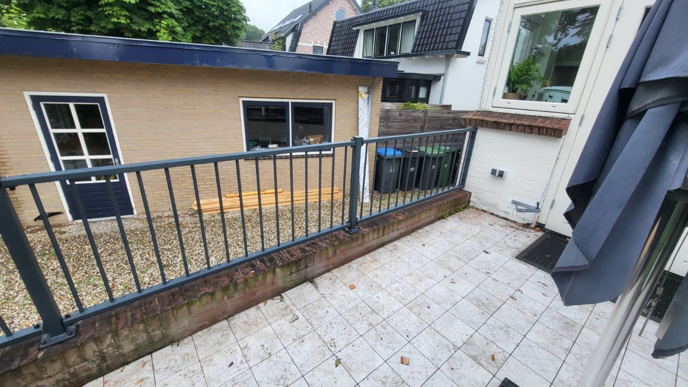 Het verhoogde terras langs de zijgevel met de nieuwe stalen balustrade