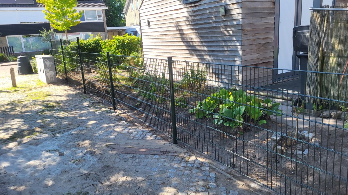 Dubbelstaafmat hekwerk in RAL 6009 groen langs een border in Borne