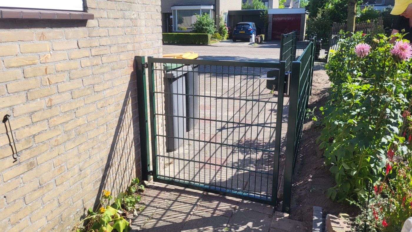 Op maat gemaakte dubbelstaafmat poort in RAL 6009 tussen woning en border