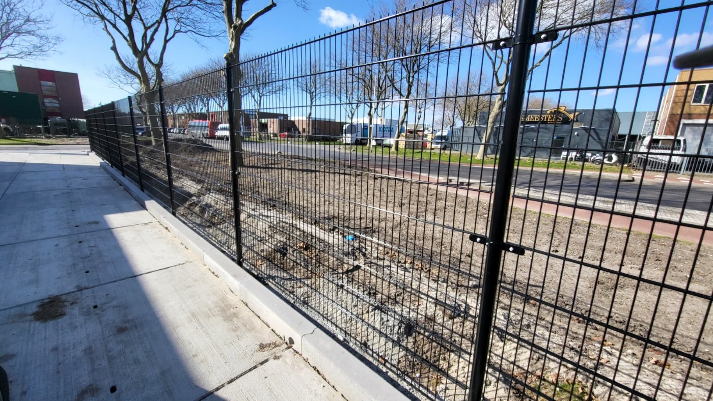Zwart dubbelstaafmat hekwerk langs een bedrijfsterrein op Urk