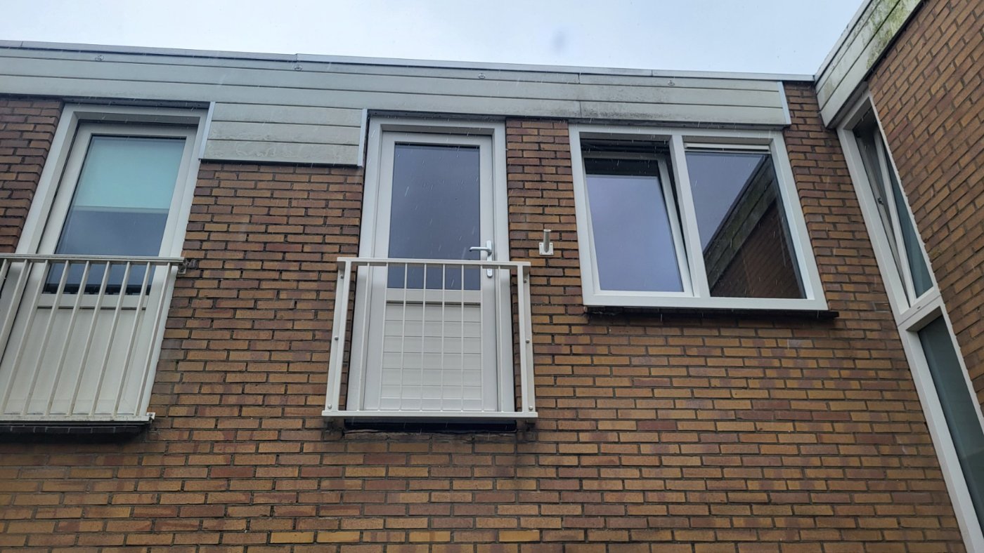 Cremewit Frans balkonhekwerk naast de witte kozijnen van de woning
