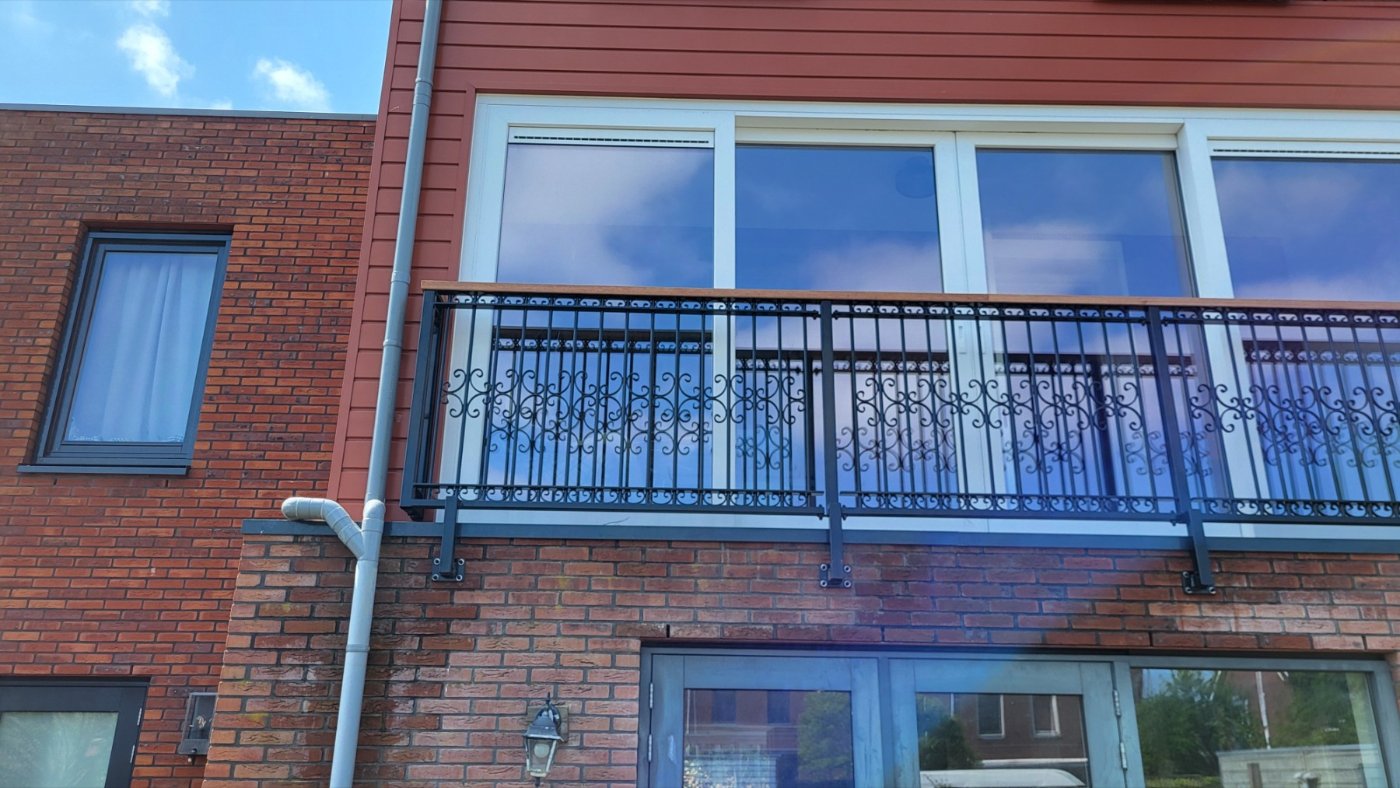 Zwarte Franse balkonhekken met sierkrullen aan een nieuwbouwblok in Almere