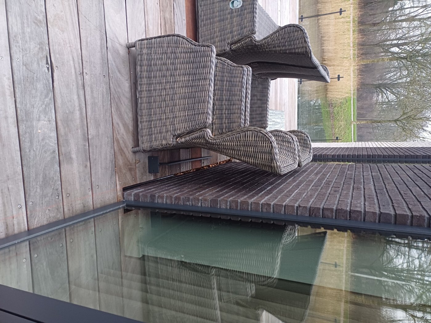 Loungemeubels op het terras achter de glazen balustrade