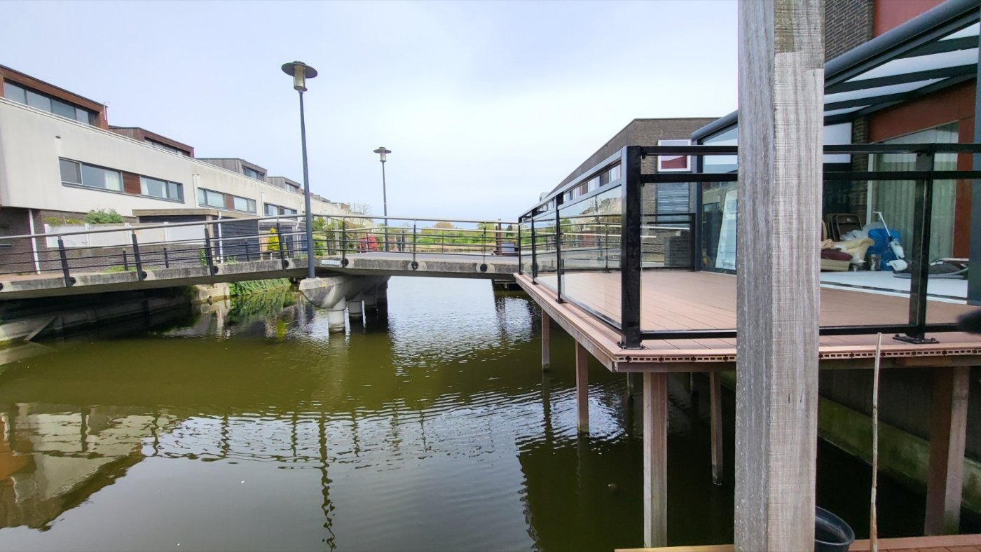 Het terras met glazen balustrade steekt uit over het water