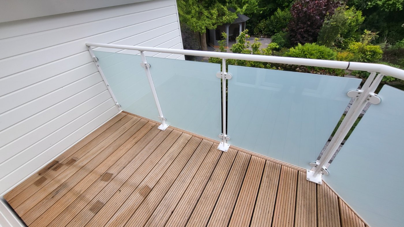 Witte glazen balustrade rond een dakterras met nieuwe houten vlonder in Almere