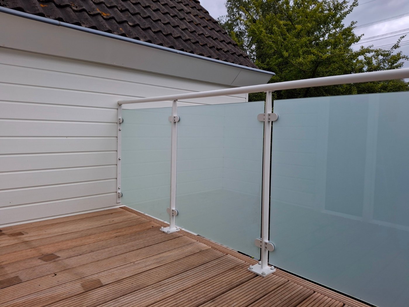 Glaspanelen in glasklemmen tussen witte staanders met ronde handregel