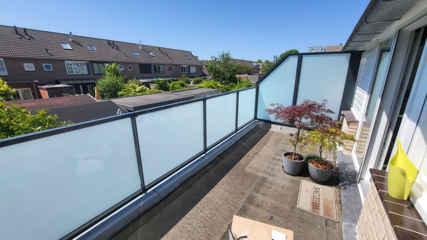 Glazen balustrade van matglas met antracietgrijs frame op een balkon in Voorschoten