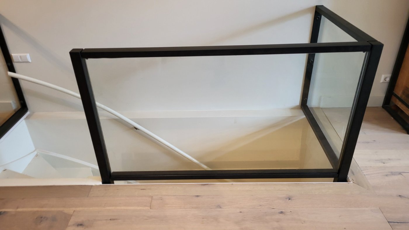 Trapgat met glazen balustrade en zwart stalen staanders van bovenaf gezien