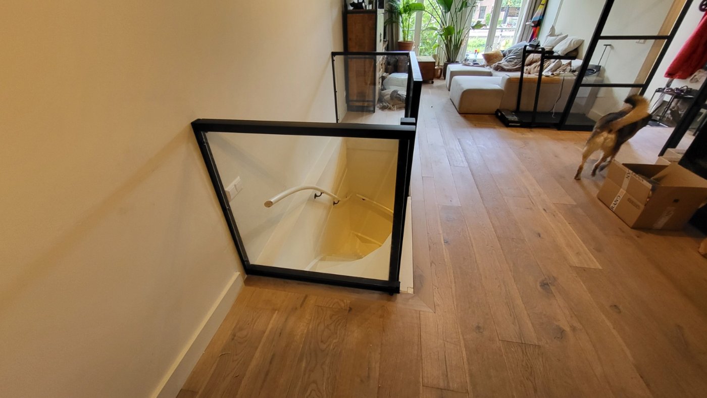 Gelaagd glas in zwarte aluminium glasprofielen langs het trapgat