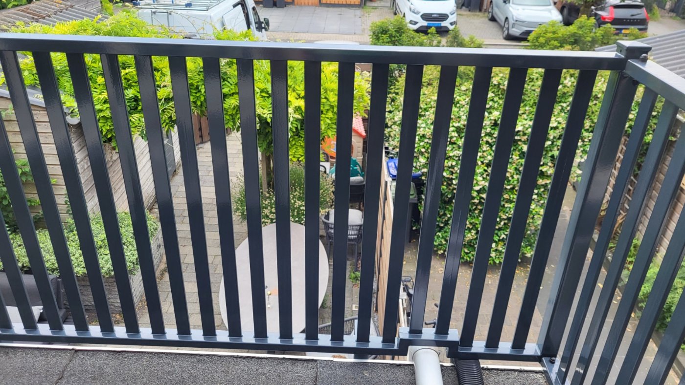 Doorkijk tussen de lamellen vanaf het terras naar de straat