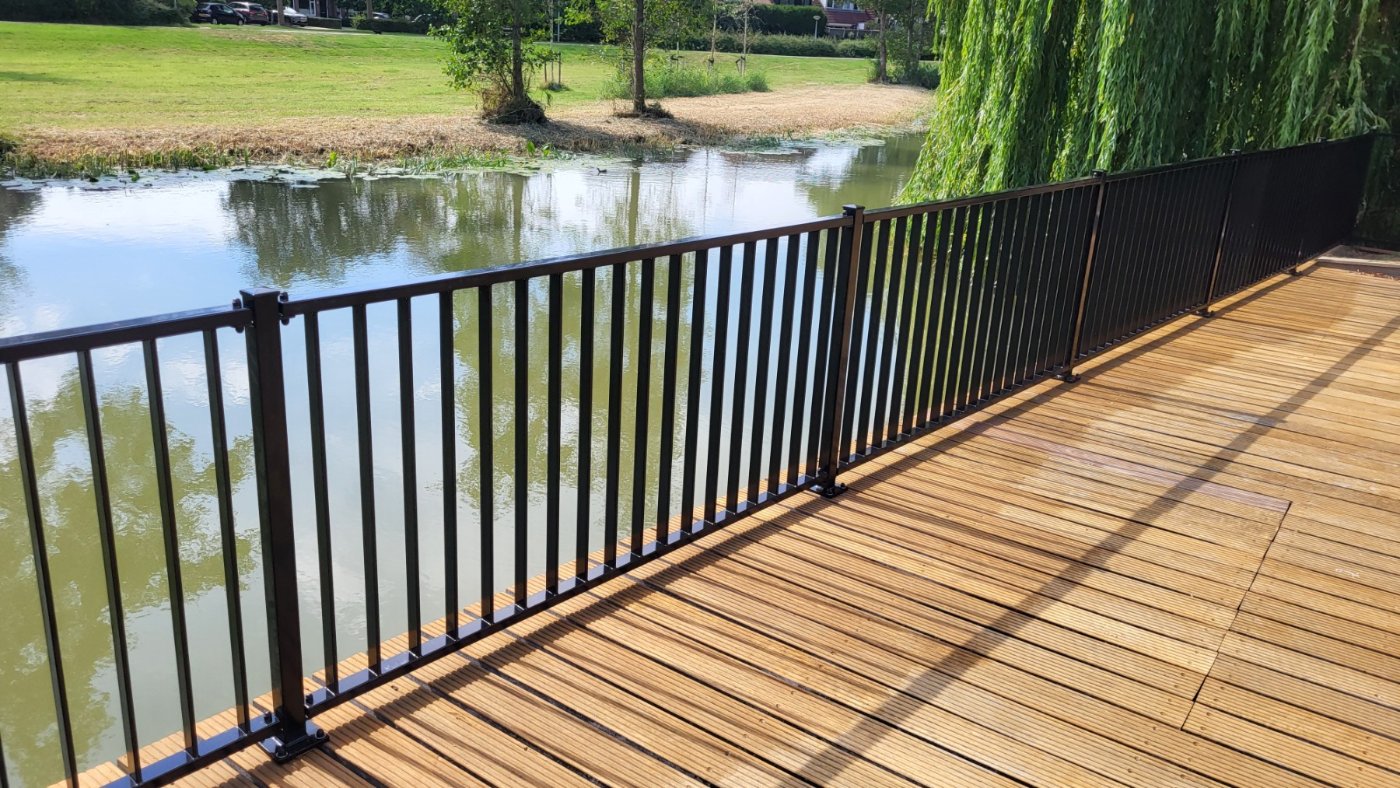 Zwarte stalen balustrade langs de waterkant van het houten terras