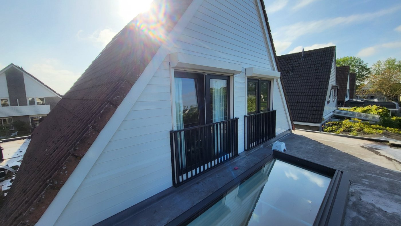 De woning met de twee Franse balkons in de topgevel, gezien in de late zon