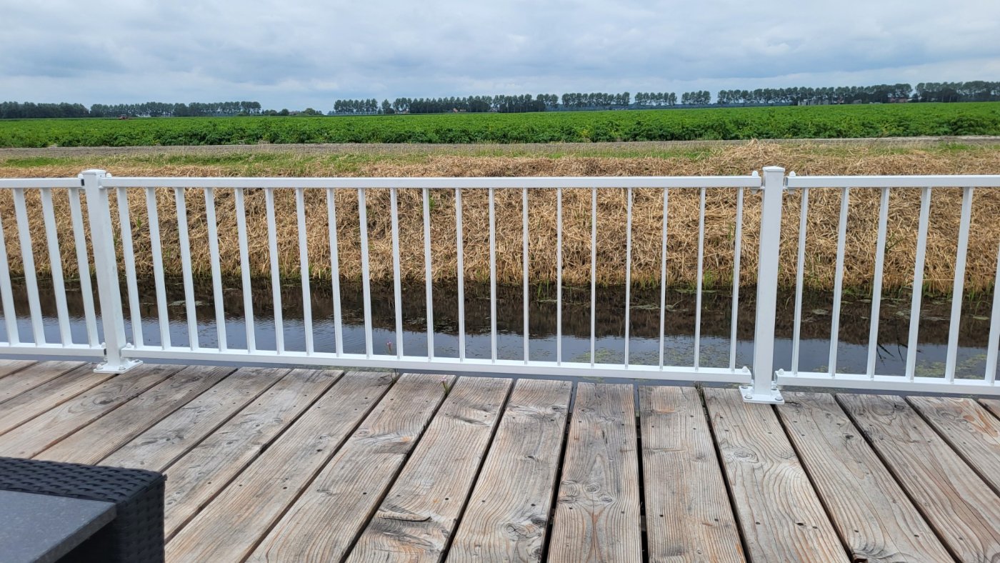 Wit striphekwerk in RAL 9016 op een houten terras met uitzicht over de polder in Urk