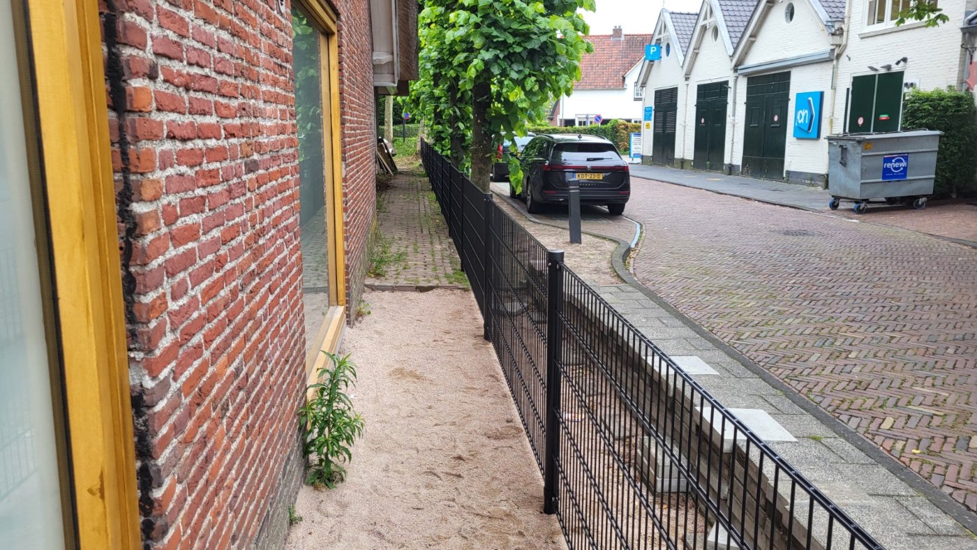 Zwart dubbelstaafmat hekwerk in RAL 9005 langs een pand in het dorpscentrum van Blaricum