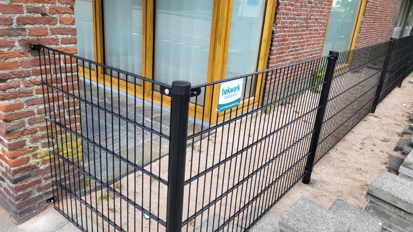 Dubbelstaafmat paneel en paal tegen het oude metselwerk van het pand